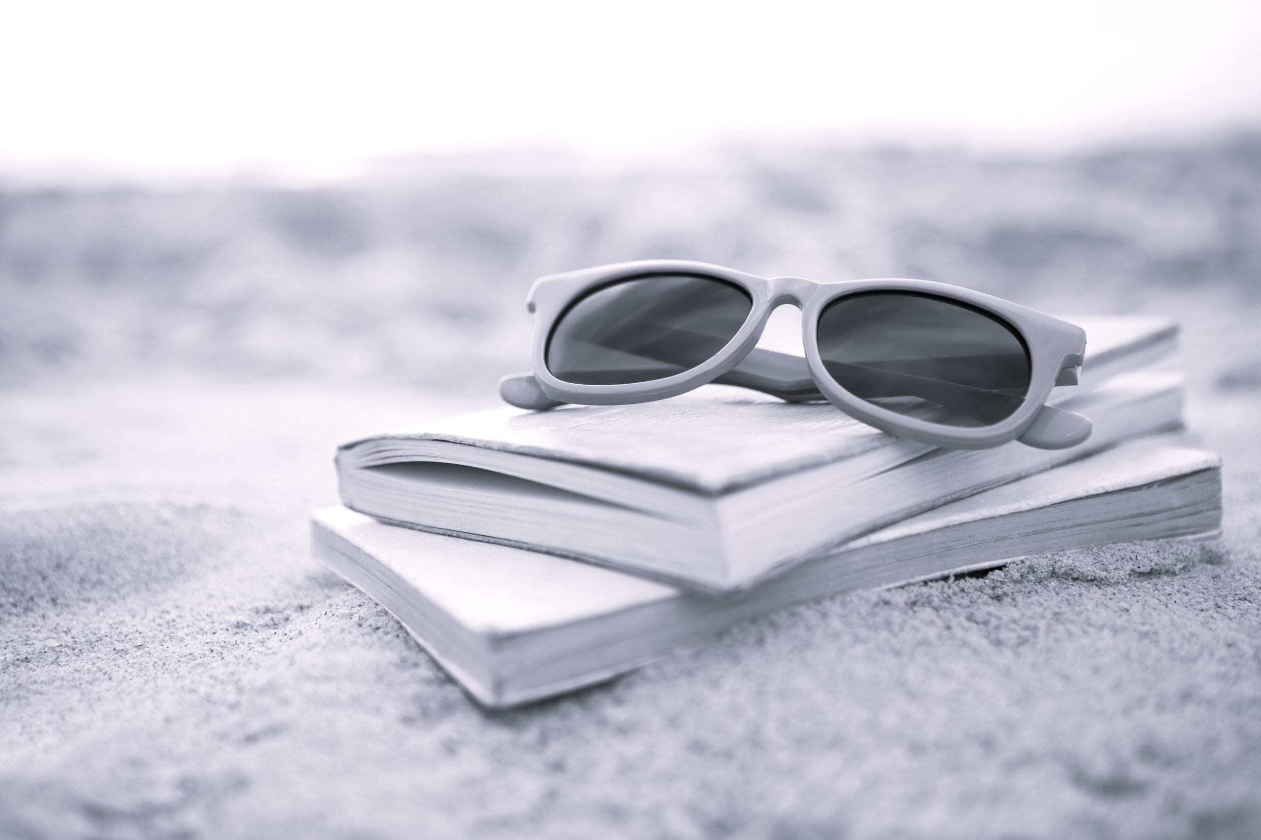Sunglasses and books on sand at beach 10 lecturas para verano