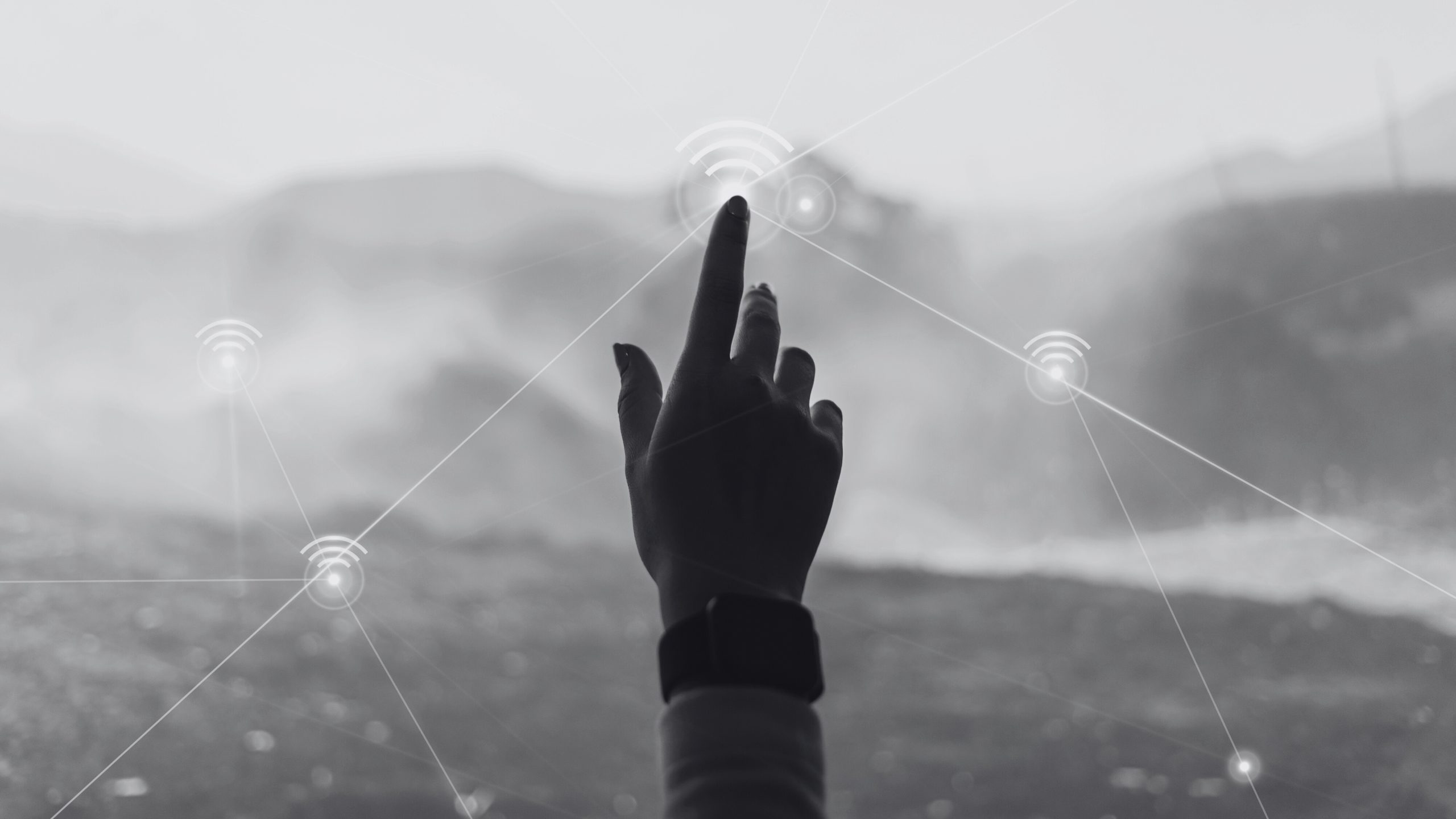 Una mano presiona un boton tactil en un ventanal con una montaña de fondo.